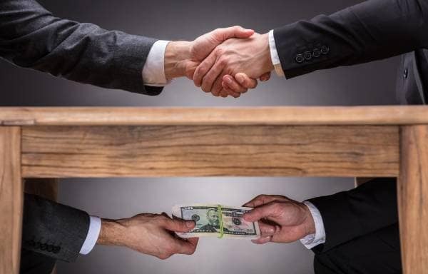 Two men shaking hands and giving money.